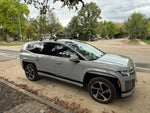 Silver SUV parked on a street with trees and houses in the background